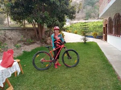 a girl is standing next to a bike on the grass at Hotel Quilla Wasi in Lunahuaná