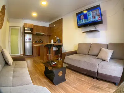 a living room with a couch and a tv on the wall at Apartamento a pasos de la Plaza Cusco Inlove in Cusco