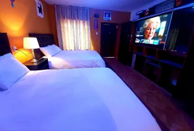a hotel room with two beds and a flat screen tv at wayra house san blas in Cusco