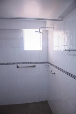 a white tiled bathroom with a window and a shower at Tunupa Lodge Hotel in Ollantaytambo