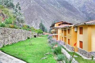 a building with a stone wall next to a yard at Tunupa Lodge Hotel in Ollantaytambo