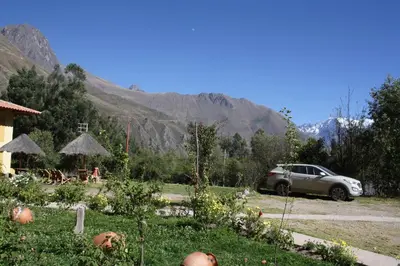 a car parked in a garden with mountains in the background at Tunupa Lodge Hotel in Ollantaytambo