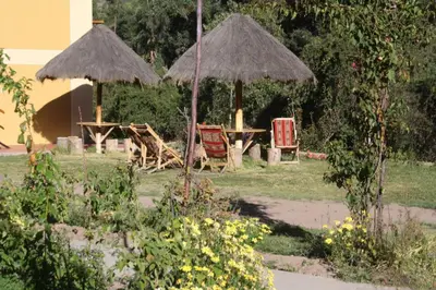 two umbrellas and a table and chairs in a garden at Tunupa Lodge Hotel in Ollantaytambo