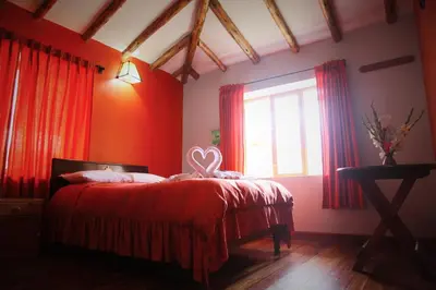 a bedroom with a bed with red walls and a window at Tunupa Lodge Hotel in Ollantaytambo