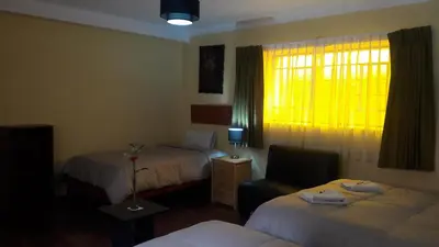 a hotel room with two beds and a window at Kurumi Hostel in Cusco