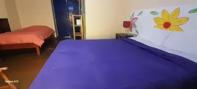a bedroom with a purple bed with a flower on the wall at Kurumi Hostel in Cusco