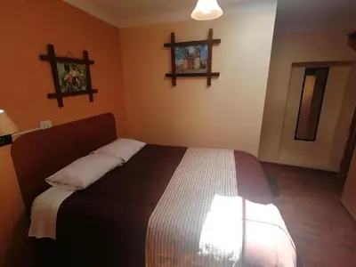 a bedroom with a bed and two crosses on the wall at Conquista Cusco in Cusco