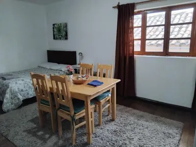 a dining room with a table and chairs and a bed at Nice studio in historic center with private bathroom and kitchen! in Cusco