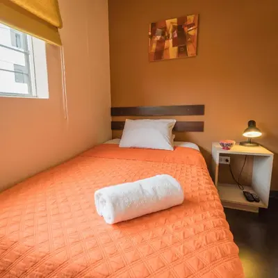 a bedroom with a bed with a white towel on it at B&B Wasi Airport Lima in Lima