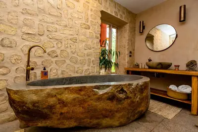 a large stone tub in a bathroom with a stone wall at NUNA by DCO in Urubamba