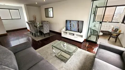 a living room with a couch and a table and a tv at Hermoso departamento en el Corazón de Miraflores in Lima