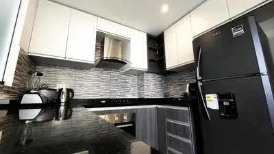 a kitchen with a black refrigerator and white cabinets at Hermoso departamento en el Corazón de Miraflores in Lima