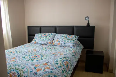 a bed with a quilt and a pillow on it at Departamento 100 m2 con luz natural y Seguridad 24h in Lima