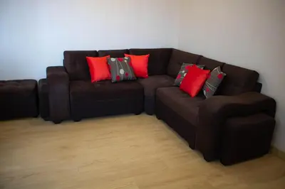 a brown couch with red and green pillows on it at Departamento 100 m2 con luz natural y Seguridad 24h in Lima