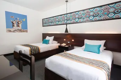 a hotel room with two beds with blue pillows at SACHA Centric in Cusco