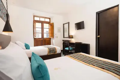 a hotel room with two beds and a desk at SACHA Centric in Cusco