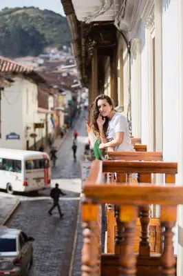 a woman sitting on a balcony talking on a cell phone at SACHA Centric in Cusco