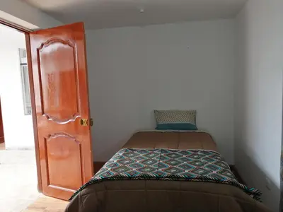 a small bedroom with a bed and a door at Casa ValPer in Cusco