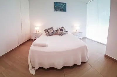 a white bedroom with a large white bed with pillows at Departamento de playa - Condominio OCEAN REEF - SAN BARTOLO in San Bartolo