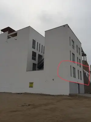 a white building with a red circle on the side of it at DEPARTAMENTO SAN BARTOLO-2dormitorios in Lima