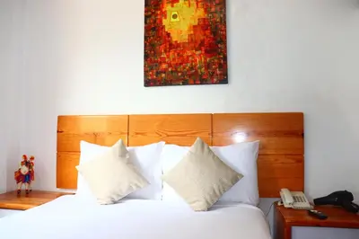 a bedroom with a bed with white pillows and a phone at Fenix Hotel Machupicchu in Machu Picchu