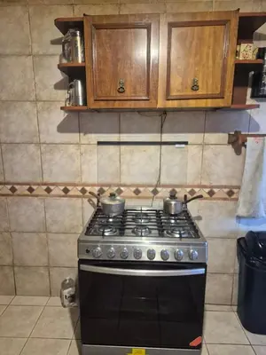 a kitchen with a stove and wooden cabinets at Garden House Miraflores in Lima