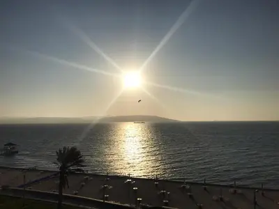 a bird flying over the ocean with the sun in the sky at Paracas Penthouse first line Boardwalk in Paracas