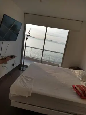 a bedroom with a large bed and a large window at Paracas Penthouse first line Boardwalk in Paracas