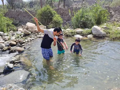a man and two children walking in a river at Cabañas o habitación en Fundo Huabayor in Lima