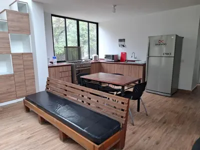 a kitchen with a bench and a table and a refrigerator at Cabañas o habitación en Fundo Huabayor in Lima