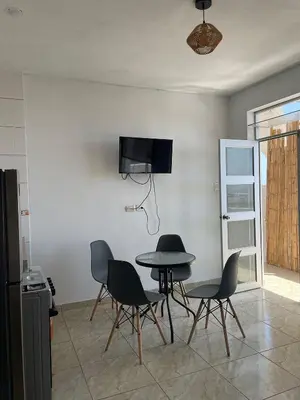 a room with a table and chairs and a tv on a wall at Olas inn in Asia
