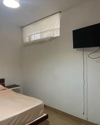 a bedroom with a bed and a television on a wall at Olas inn in Asia