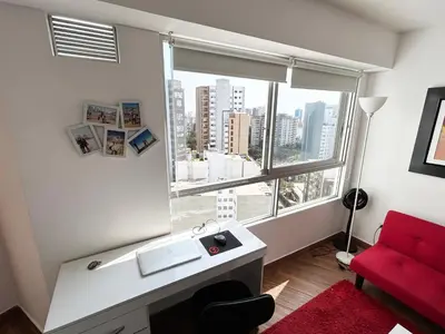 a bathroom with a red couch and a large window at Apartamento moderno con vistas, WiFi gratis y cocina equipada in Lima