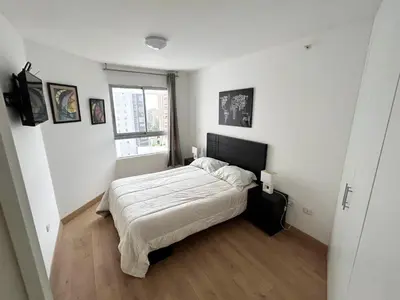 a white bedroom with a bed and a window at Apartamento moderno con vistas, WiFi gratis y cocina equipada in Lima
