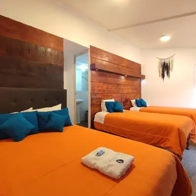 a bedroom with two beds with orange sheets at CASA SAPANTIANA, cerca a Sacsayhuaman in Cusco