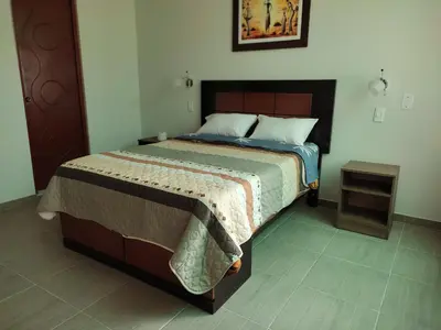 a bedroom with a large bed with a wooden headboard at Hotel ARKONA in Huancayo