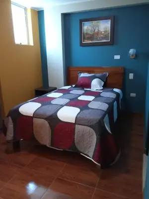 a bedroom with a bed with a quilt on it at Hotel ARKONA in Huancayo
