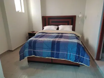 a bed with a blue and white comforter in a room at Hotel ARKONA in Huancayo