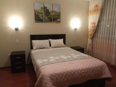a bedroom with a bed with two night stands and two lamps at Hotel ARKONA in Huancayo