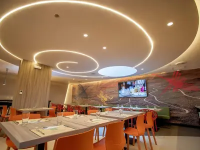 a dining room with a long table with orange chairs at ibis Styles Lima Benavides Miraflores in Lima
