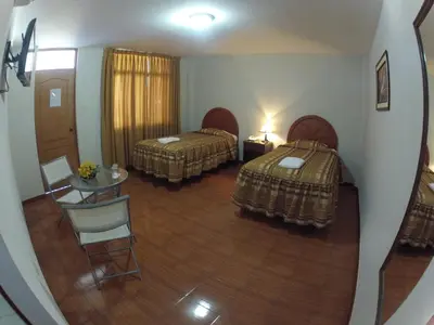 a view of a room with two beds and a table at Hotel Alegria Nasca in Nazca