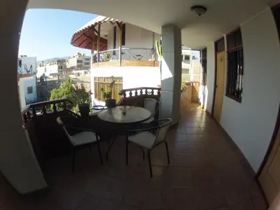 a balcony with a table and chairs and an umbrella at Hotel Alegria Nasca in Nazca