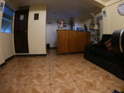 a living room with a black couch and a wooden floor at Don Feli House in Machu Picchu