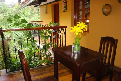 a table with a vase of yellow flowers on a balcony at Wayras Hostal in Ollantaytambo