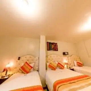 a room with two beds and two chairs in it at ANDINO HOTEL MACHUPICCHu in Machu Picchu