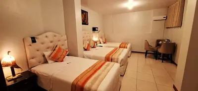 a hotel room with two beds and a table at ANDINO HOTEL MACHUPICCHu in Machu Picchu