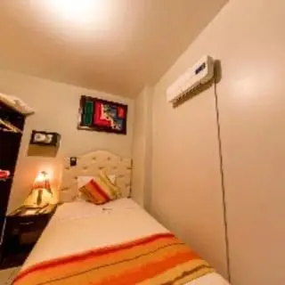 a small bedroom with a bed and a heater at ANDINO HOTEL MACHUPICCHu in Machu Picchu