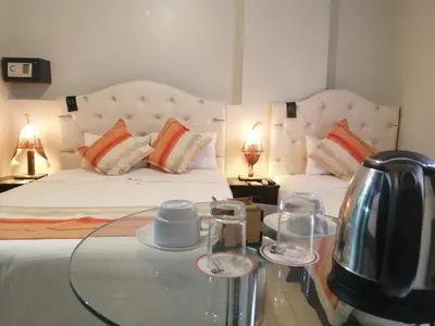 a bedroom with two beds and a glass table with a tea kettle at ANDINO HOTEL MACHUPICCHu in Machu Picchu