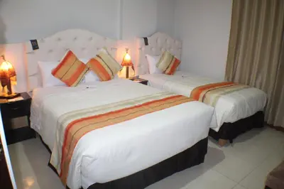 two beds in a hotel room with two lamps at ANDINO HOTEL MACHUPICCHu in Machu Picchu