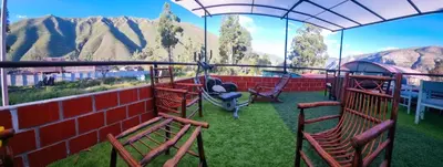 a balcony with chairs and a view of the mountains at Valle verde, Hostel & camping in Urubamba